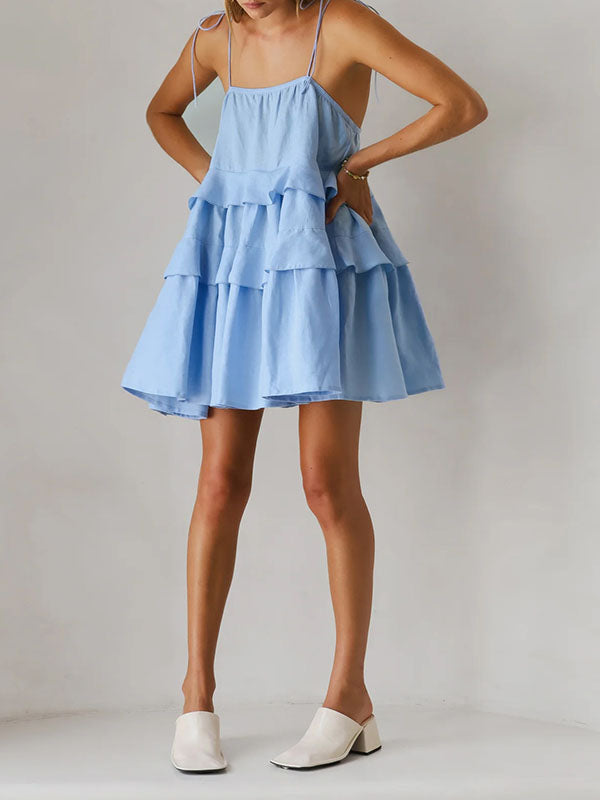 Robe courte ample superposée plissée nouée taille haute, dos nu, à fines bretelles, couleur unie