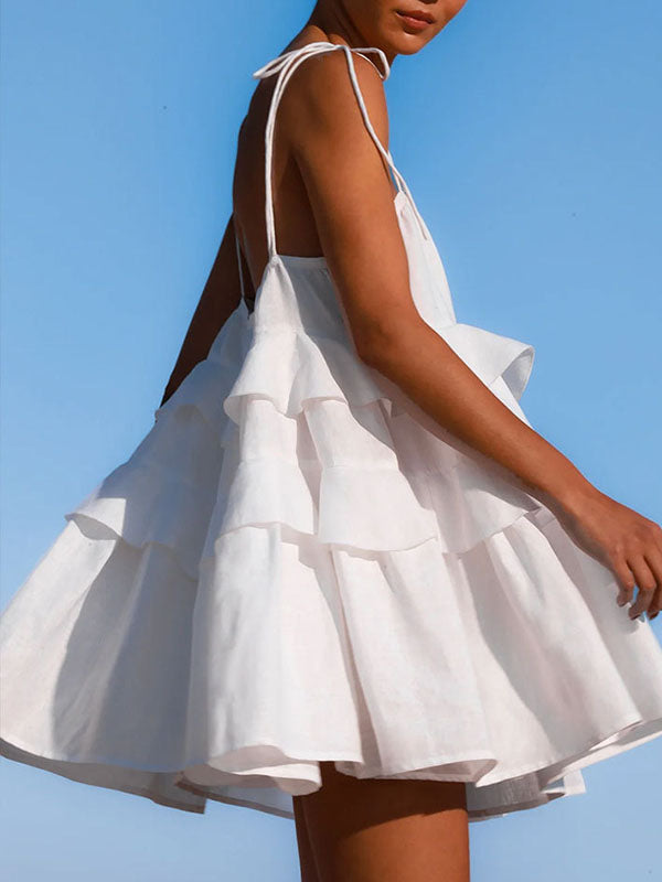 Robe courte ample superposée plissée nouée taille haute, dos nu, à fines bretelles, couleur unie