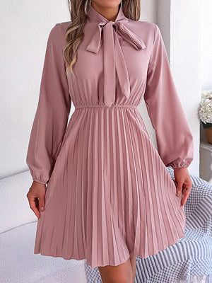 Robe courte ample plissée nouée à manches longues, à col cheminée, couleur unie