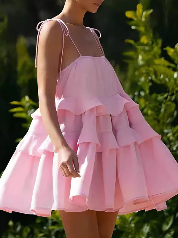 Robe courte ample superposée plissée nouée taille haute, dos nu, à fines bretelles, couleur unie