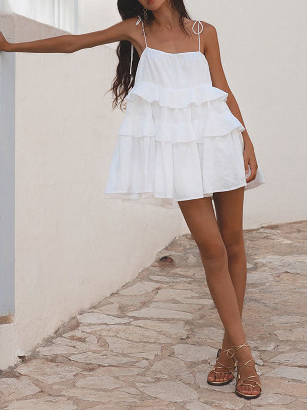 Robe courte ample superposée plissée nouée taille haute, dos nu, à fines bretelles, couleur unie
