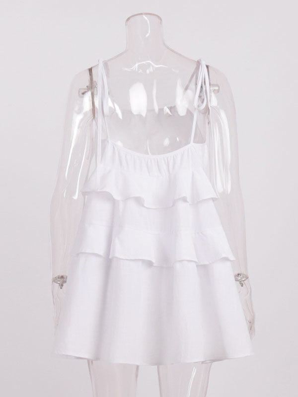 Robe courte ample superposée plissée nouée taille haute, dos nu, à fines bretelles, couleur unie