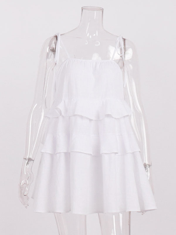 Robe courte ample superposée plissée nouée taille haute, dos nu, à fines bretelles, couleur unie