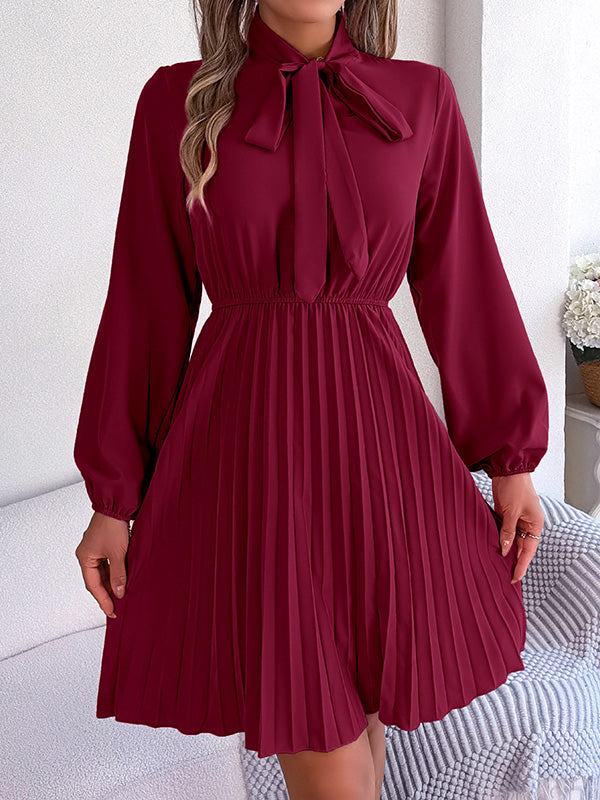 Robe courte ample plissée nouée à manches longues, à col cheminée, couleur unie